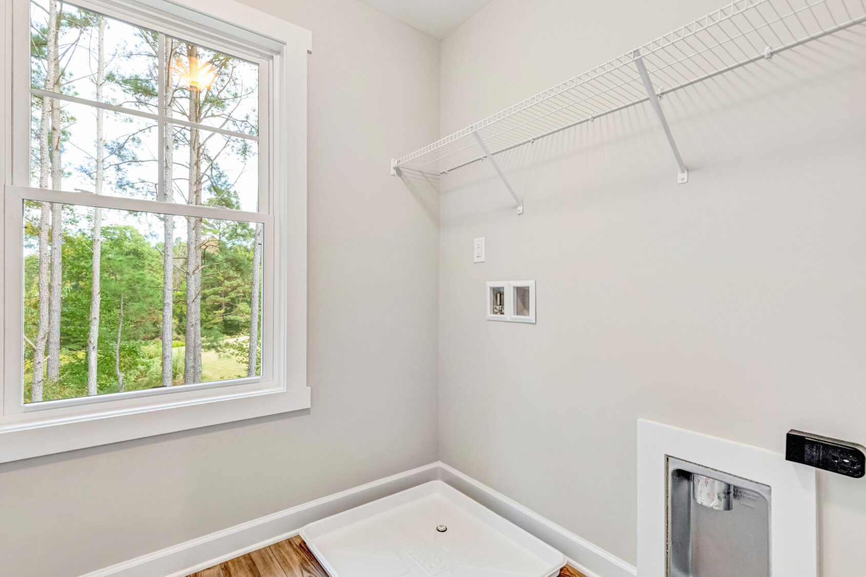 Bright laundry room with a large window, wire shelf, hookups, and a pet door in the wall.