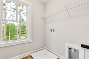 Bright laundry room with a large window, wire shelf, hookups, and a pet door in the wall.