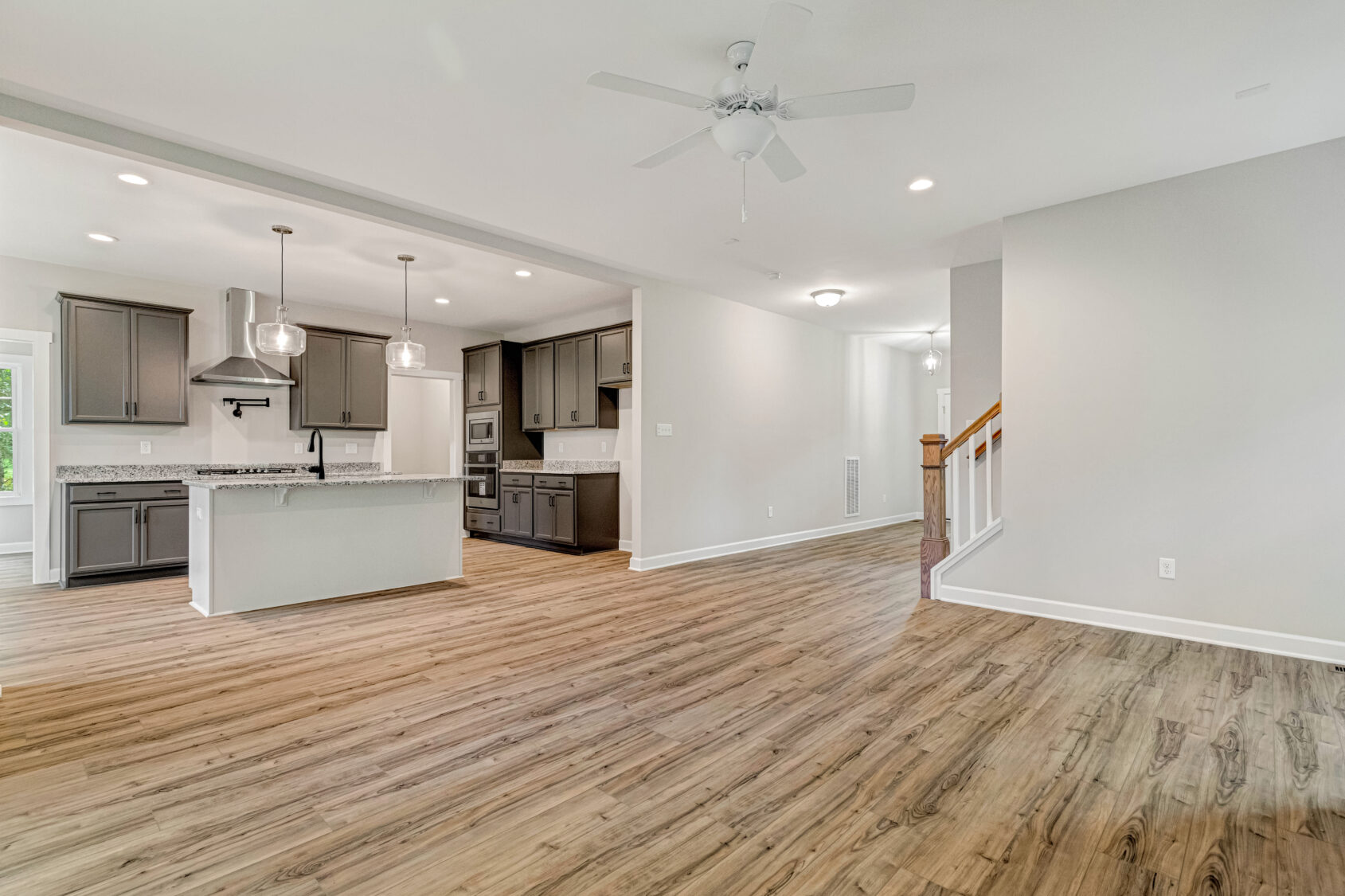 Spacious open-concept kitchen and living area with wood floors, gray cabinets, and ceiling fan.