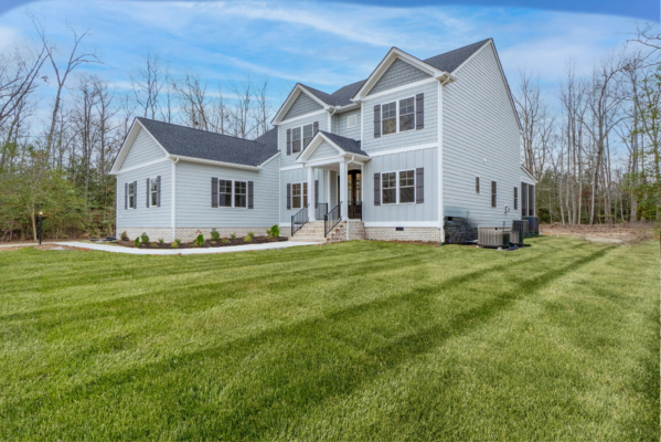 Two-story white house in Richmond with a dark roof, large windows, and a well-kept lawn under a blue Virginia sky.