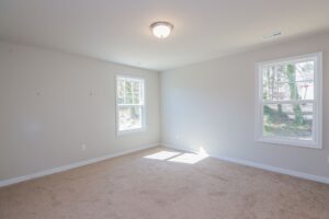 Empty room with beige carpet, light gray walls, and two windows found in new homes in Richmond VA.
