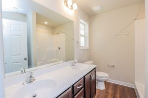 Bright bathroom with double sinks, large mirror, and wooden floor found in new homes in Richmond VA.