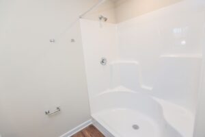 White shower stall with built-in seat and chrome fixtures; perfect for new homes in Richmond VA.