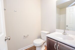A bathroom in one of the new homes in Richmond VA with a toilet, sink, mirror, and empty towel and paper holders.
