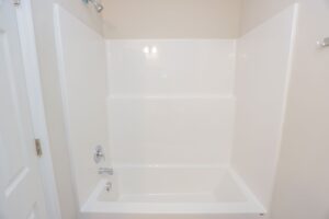 White bathtub and shower with smooth, clean surround in a neutral-colored bathroom—perfect for new homes in Richmond, VA.