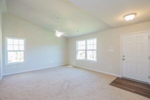 Bright, empty room with beige carpet, ceiling fan, and large windows—perfect for new homes in Richmond VA.