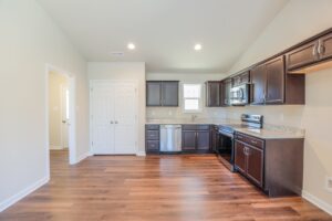 Modern kitchen with dark wood cabinets, stainless appliances, and wood floors—perfect for new homes in Richmond VA.