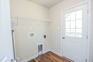 Laundry room in new homes in Virginia features a door, washer hookups, shelf, pet door, and plenty of sunlight.