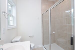 Modern bathroom in one of the new homes in Virginia, featuring a glass shower, sink, and a window for natural light.