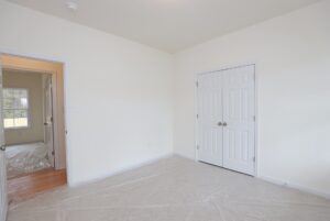 Empty room with white walls, double closets, and open door to sunlit hallway—perfect for new homes in Richmond VA.