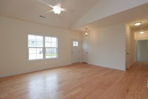 Bright empty living room with light wood floors, ideal for new homes in Richmond VA, cream walls, and ceiling fan.