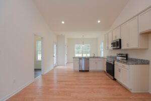 Bright modern kitchen in new homes in Richmond VA with light wood floors, white cabinets, and stainless steel appliances.