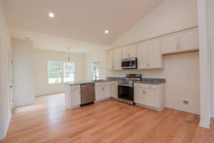 Modern kitchen in new homes in Richmond VA with light wood floors, white cabinets, and stainless steel appliances.