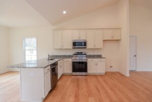Modern kitchen with stainless appliances, white cabinets, and wood floors—perfect for new homes in Richmond VA.