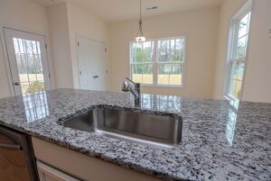Granite kitchen island with sink and faucet, perfect for new homes in Richmond VA with bright windows in the background.