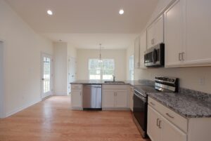 Modern kitchen in new homes in Richmond VA with light wood floors, white cabinets, and stainless steel appliances.