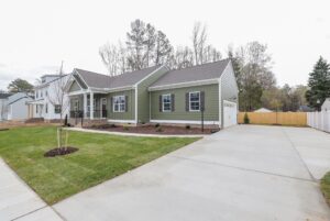 Green single-story house with white trim, porch, and wide driveway—perfect for new homes in Richmond VA.