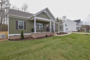 Single-story green house with white trim and porch, typical of charming new homes in Richmond VA.
