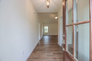 Open wooden door reveals a bright hallway with wood floors in one of the beautiful new homes in Richmond, VA.