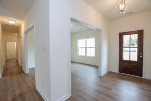 Bright hallway with wooden floors, white walls, and a brown door—perfect for new homes in Richmond VA.
