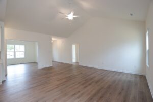 Empty living room with wood floors and vaulted ceiling, perfect for new homes in Richmond VA, connects to a bright room.