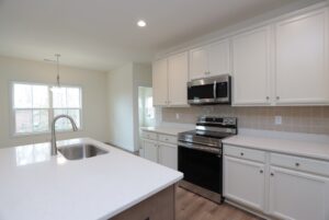 Modern kitchen in new homes in Richmond VA, featuring white cabinets, stainless steel appliances, and a large island.