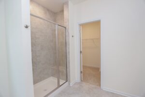 Modern bathroom with a glass shower, next to an open door in walk-in closet—perfect for new homes in Richmond VA.