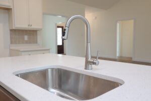 Modern kitchen in new homes in Richmond VA with a stainless steel sink and faucet set in a white quartz countertop.