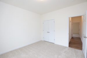 Empty room in one of the new homes in Richmond VA, featuring beige carpet, white walls, and double closet doors.