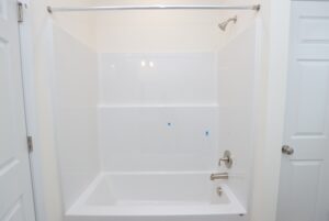 Lot 30 Poplar Village: White bathtub and shower combo with chrome fixtures, surrounded by white walls and dual doors.