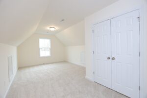 Bright attic room with beige carpet, white walls, and closet—perfect for new homes in Richmond VA.