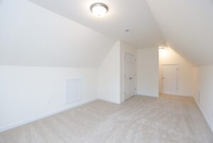 Empty attic room with sloped ceiling, beige carpet, and white walls—perfect for new homes in Richmond VA.