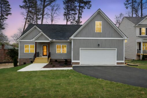 Gray suburban house with white trim, double garage, and neat lawn—explore new homes in Richmond VA at sunset.