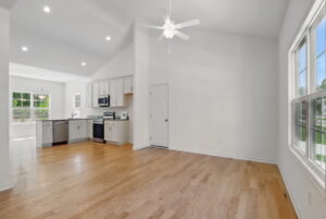 Bright open kitchen and living area at The Charles, with hardwood floors, white walls, and abundant natural light.