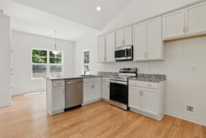 Modern kitchen in Poplar Village with white cabinets, stainless appliances, and large windows for natural light.