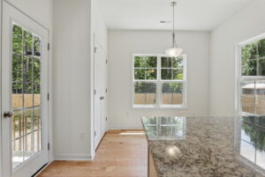 Bright Poplar Village kitchen with granite countertop, wood floor, and large windows, by Charles.