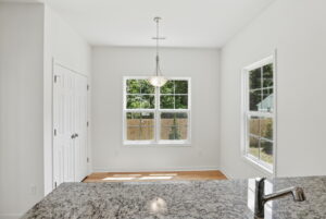 Bright kitchen at The Charles with granite countertop, pendant light, and large windows overlooking a fenced backyard.