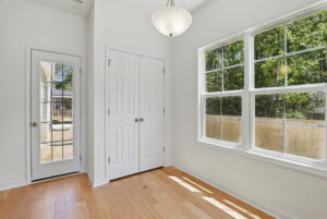 Bright room at Poplar Village with wood floor, double closets, large window, and glass door leading outside.