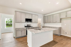 Modern Somerset Hill kitchen with gray cabinets, white island, granite counters, stainless appliances, and wood flooring.