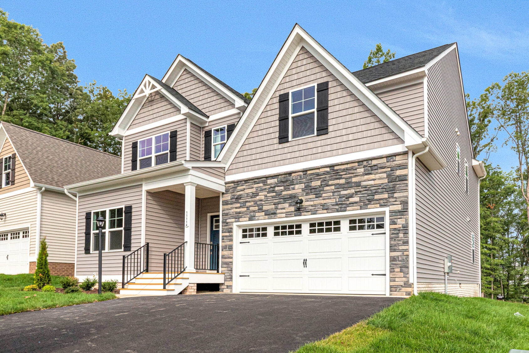 Somerset Hill two-story home with gray siding, stone accents, white trim, and a double garage on a sunny day.