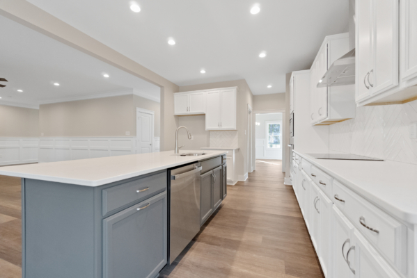 Modern kitchen in new homes in Richmond featuring white cabinetry, gray island, hardwood floors, and recessed lighting.