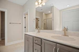 Modern bathroom with a double sink vanity, large mirror, and glass-enclosed shower. Neutral color scheme.