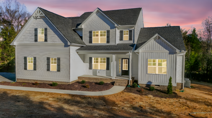 Two-story white house with gray roof, large windows, and a porch, perfect for a gallery photo at sunset.