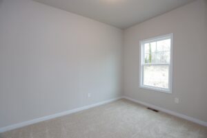 Bright empty room with beige carpet in one of the stylish new homes in Richmond VA, filled with natural light.