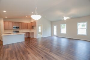 Spacious open-concept kitchen and living room in new homes in Richmond VA with wood floors and large windows.