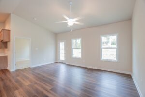 Bright empty room in one of the new homes in Richmond VA, with wood flooring, beige walls, and large sunlit windows.