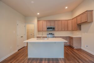 Modern kitchen in new homes in Richmond VA, with light wood cabinets, stainless appliances, and a center island.