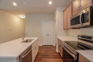 Modern kitchen in new homes in Richmond VA features stainless appliances, white countertops, and wooden cabinets.
