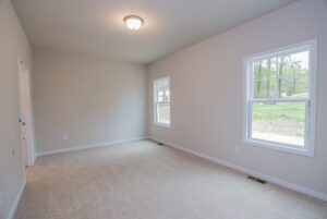 Empty room with beige carpet, gray walls, two windows, and ceiling light in new homes in Richmond VA.