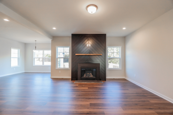 Spacious living room with a gallery-like feel, featuring a sleek dark wood fireplace, light walls, and large windows for natural light.